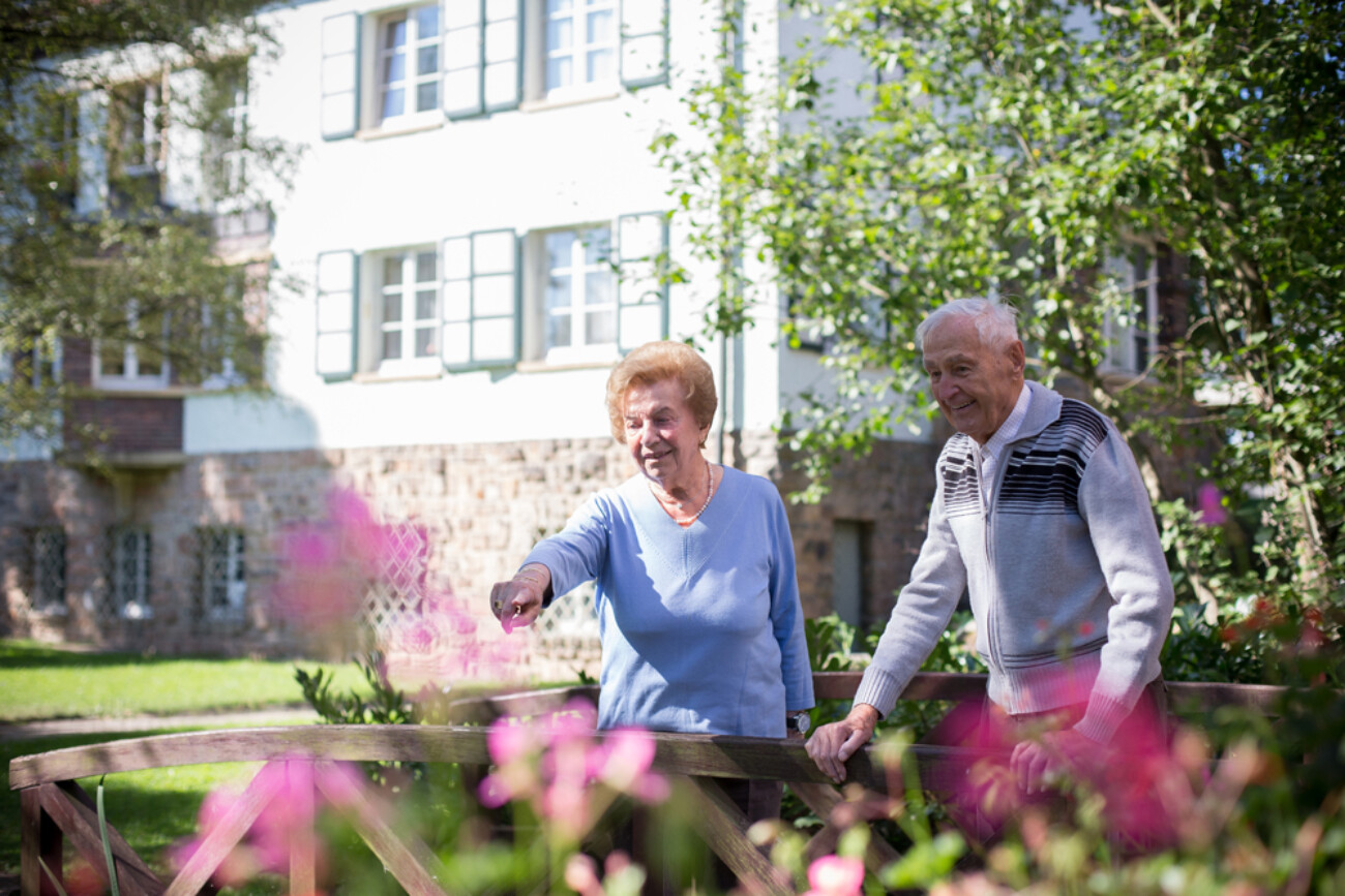 Seniorin zeigt Senior etwas im Teich – Außenbereich des Bürgerheims Schwenningen