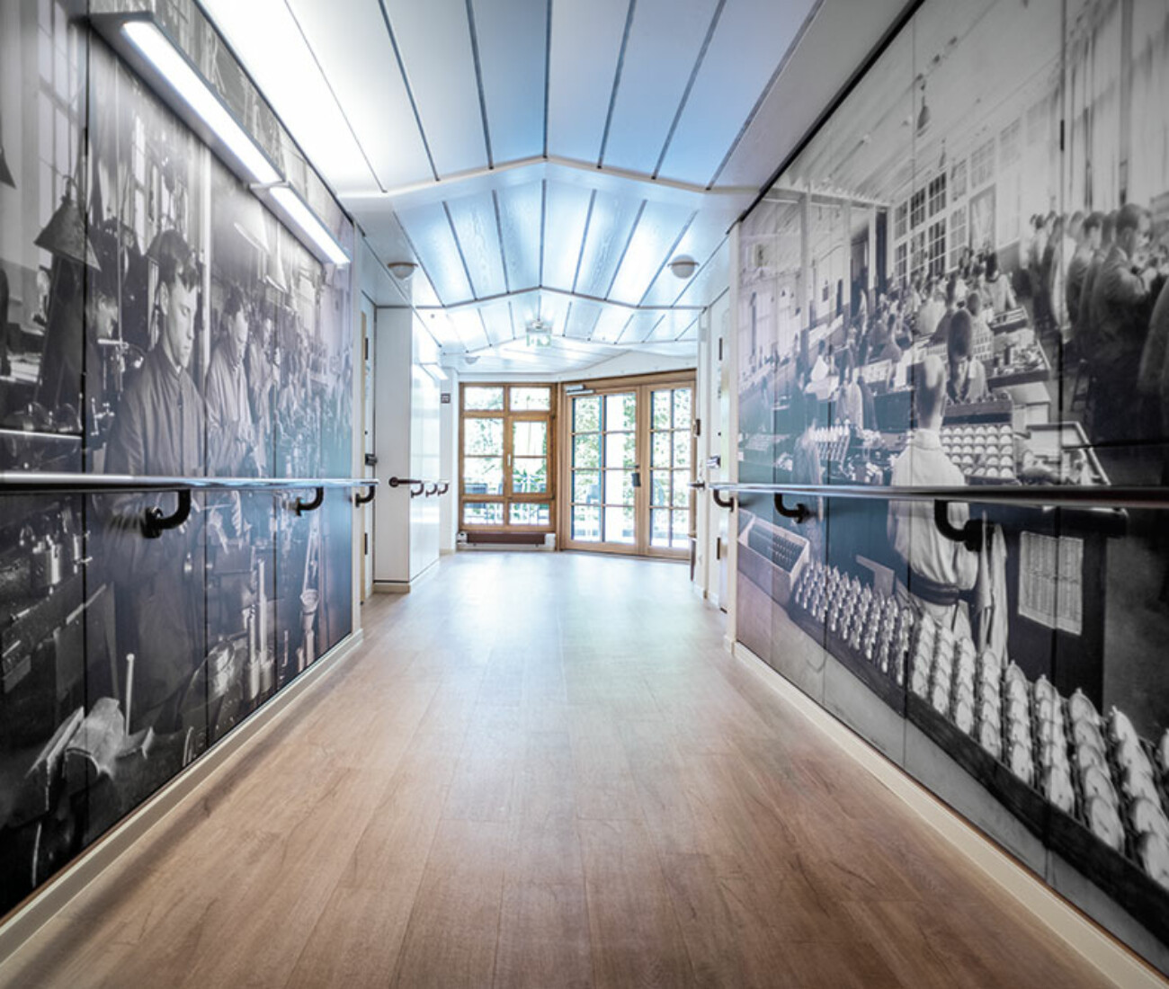 Flur im Bürgerheim Schwenningen mit hellen Wänden, Holz-Handläufen und dekorativen Schwenninger Uhrenmotiven an den Wänden