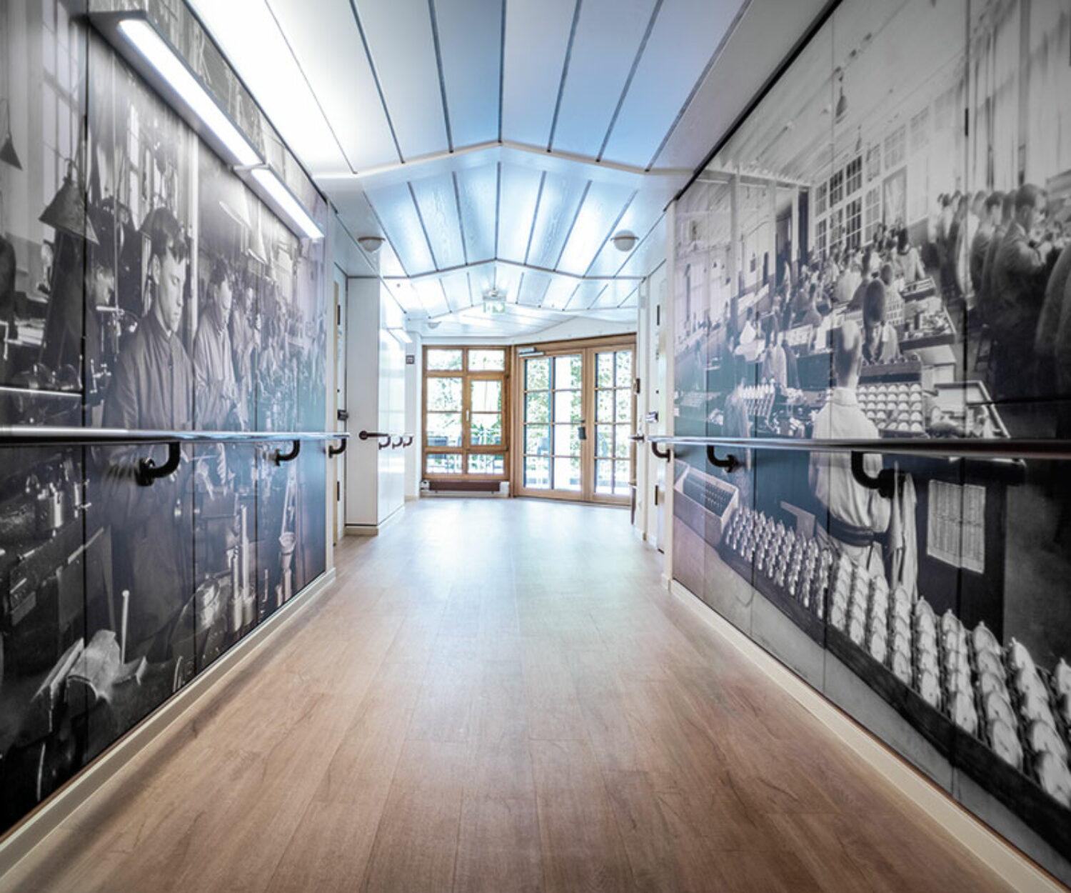 Flur im Bürgerheim Schwenningen mit hellen Wänden, Holz-Handläufen und dekorativen Schwenninger Uhrenmotiven an den Wänden