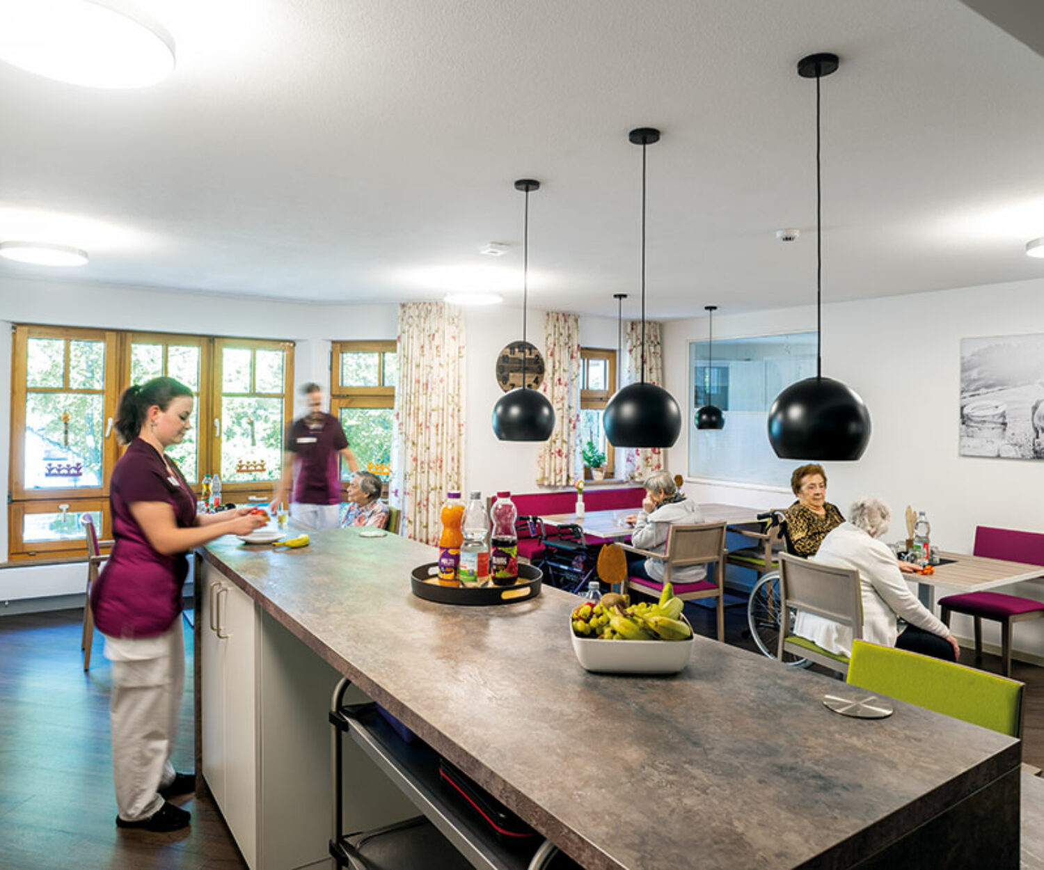 Moderne gemeinsame Wohnküche mit großer Arbeitsplatte, Stühlen und stilvollen Hängeleuchten – Gemeinschaftsküche im Bürgerheim Schwenningen