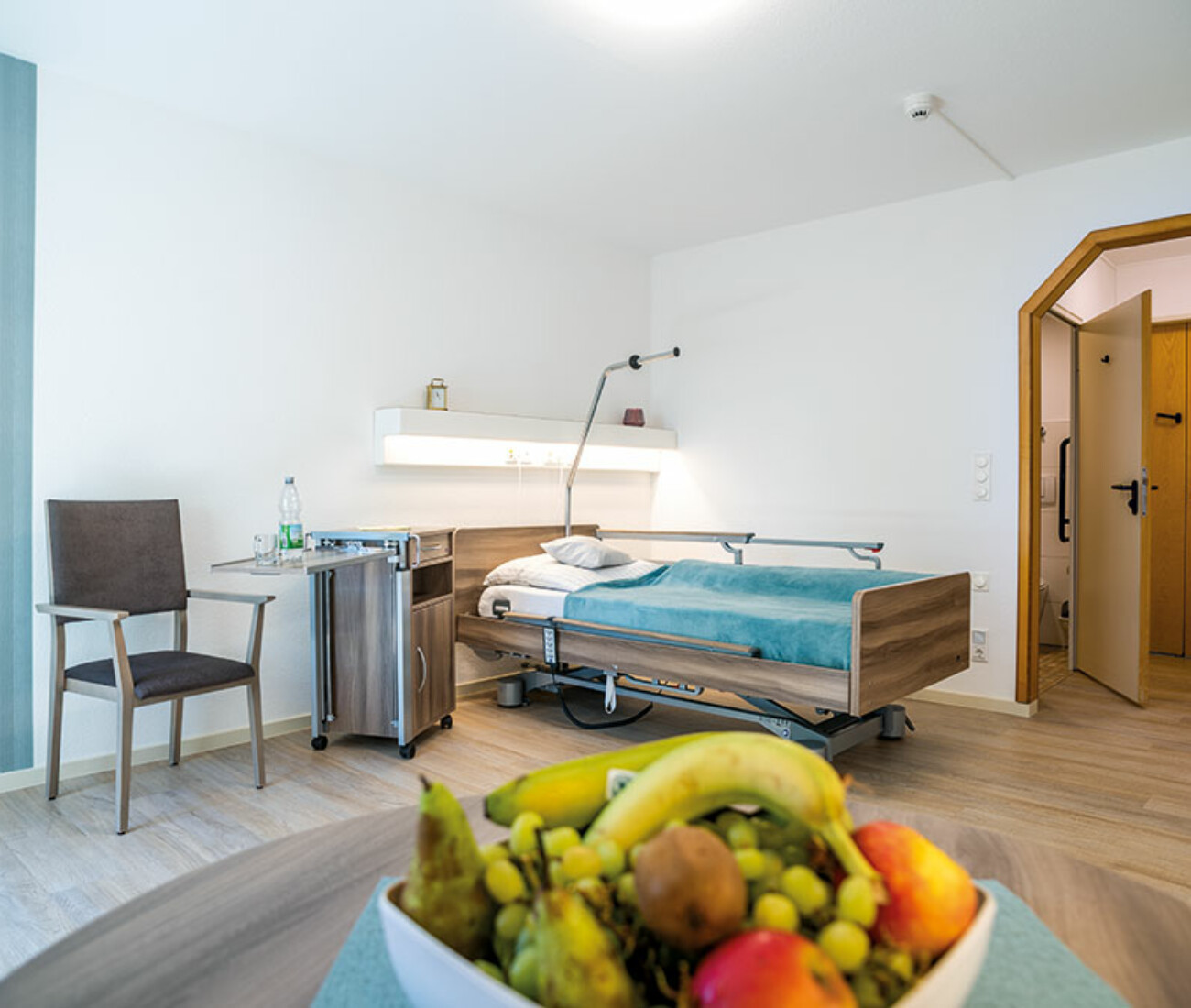 Pflegezimmer mit moderner Einrichtung, großem Fenster und Sitzmöglichkeit im Bürgerheim Schwenningen