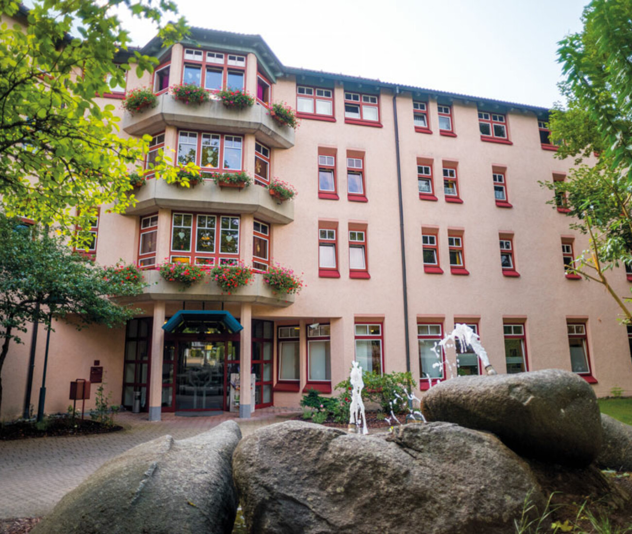 Sonnige Außenansicht vom unteren Eingang des Bürgerheims Schwenningen – Gebäude mit großzügigem grünen Vorgarten und Springbrunnen