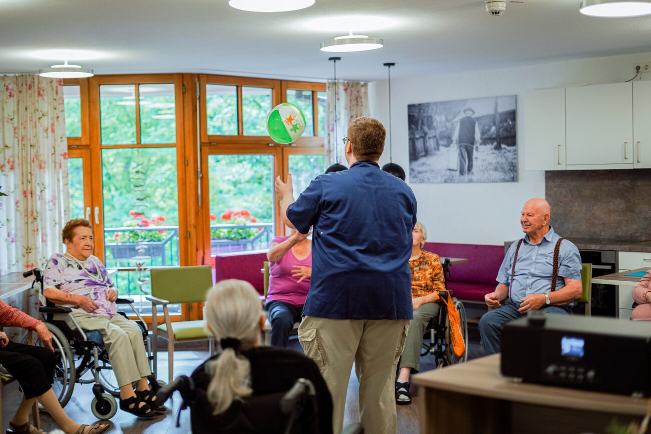 Betreuer im Bürgerheim Villingen-Schwenningen spielt fröhlich Fangen mit Senioren mit einem Wasserball