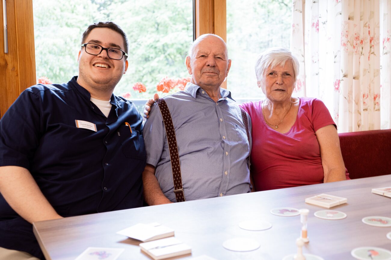 Freundlicher Betreuer im Bürgerheim Villingen-Schwenningen im Gespräch mit einer Seniorin und einem Senior an einem Tisch