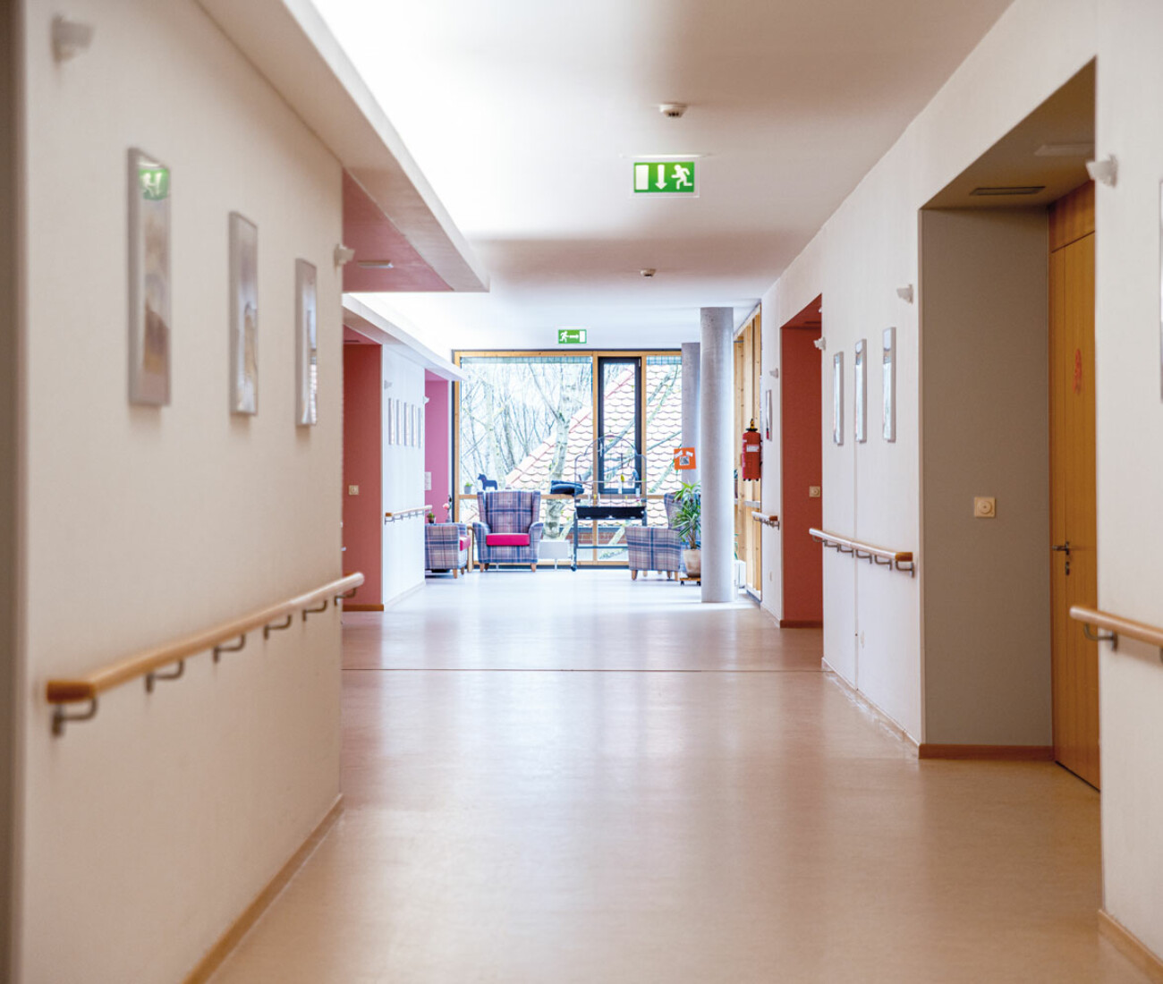 Flur im Bürgerheim Schwenningen mit hellen Wänden, Holz-Handläufen, bequemen Sitzgelegenheiten und großer Fensterfront