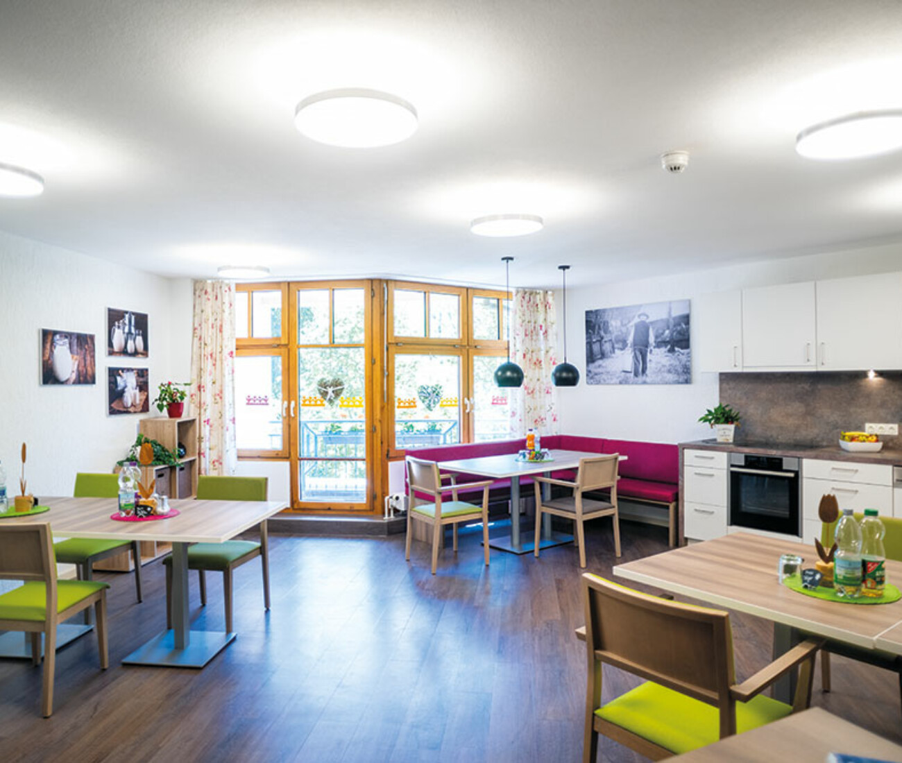 Offene Wohnküche mit großem Esstisch, Küchenzeile, Stühlen und bodentiefem Fenster