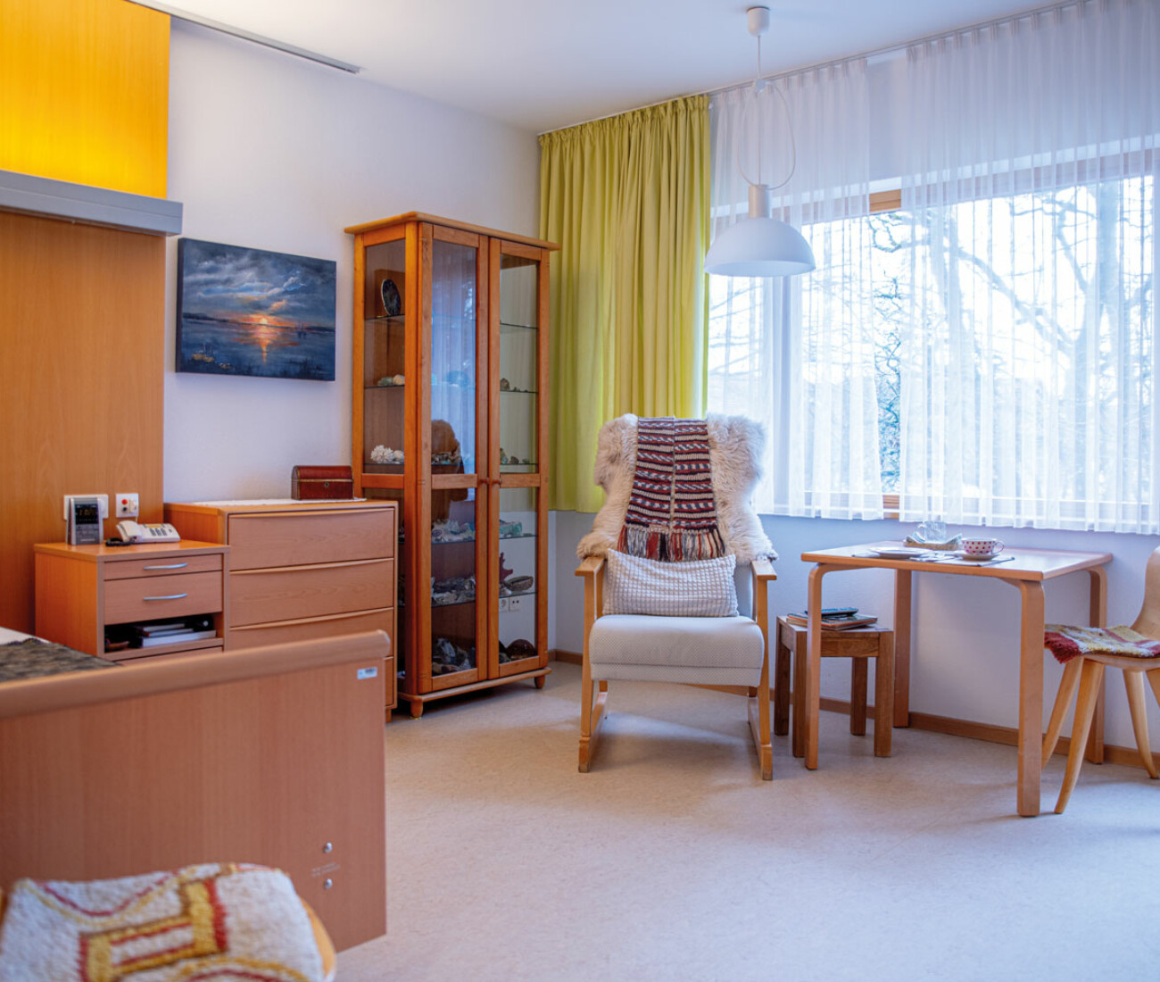 Einzelzimmer im Bürgerheim Schwenningen mit Pflegebett, Nachttisch, Kommode, Vitrine und gemütlicher Sitzgelegenheit