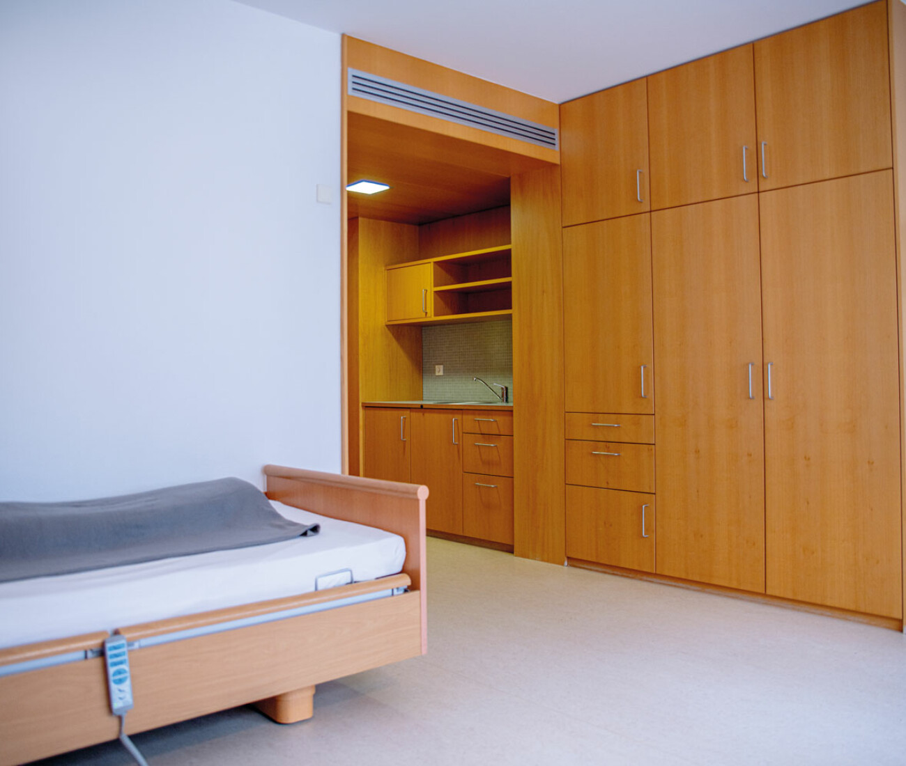 Grundausstattung eines Einzelzimmer im Bürgerheim Schwenningen mit verstellbarem Pflegebett, Nachttisch, Kleiderschrank und freundlicher, heller Einrichtung